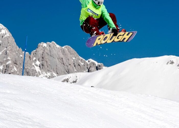 Photo by Damiano Lingauri man in green jacket riding snowboard on snow covered mountain during daytime